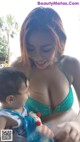 A woman in a green bikini holding a baby.