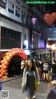 A woman walking down a city street at night with balloons.