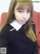 A young girl in a school uniform sitting on a red chair.