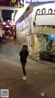 A woman standing in front of a wall covered in pictures.