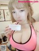 A woman in a pink bra holding a business card.