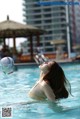 A woman in a bikini playing with a soccer ball in a pool.