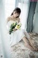 A woman in a white dress holding a bouquet of flowers.