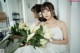 A woman in a white dress holding a bunch of white flowers.