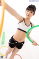 A woman in a sports bra top and shorts holding a hula hoop.