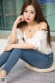 A woman sitting on the floor wearing a white top and jeans.