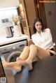 A woman sitting on top of a washing machine in a kitchen.