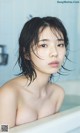 A naked woman in a bathtub with wet hair.