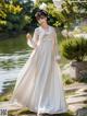 A woman in a white dress standing in front of a pond.