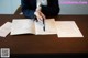 A woman sitting at a table signing a document.